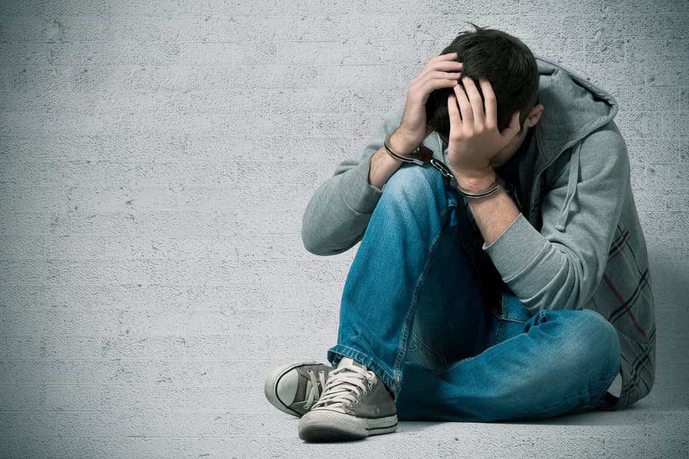 Arrested teenager with handcuffs on his hands representing the article’s topic about A Guide to California’s Division of Juvenile Justice