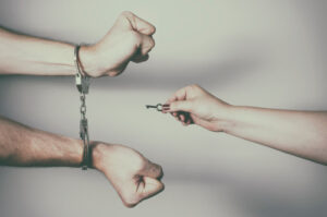 Hands, unlocking someone from handcuffs by key representing the article's topic about Bail and Own Recognizance Release