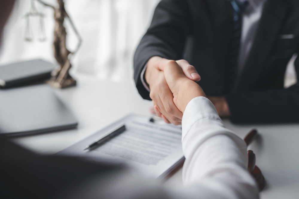 prosecutor and criminal defendant shaking hands illustrating article about What is Pre-Trial Diversion?