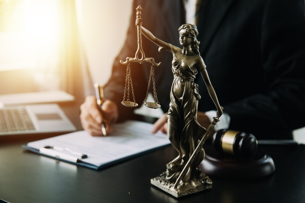 a lawyer, a contract, justice statue and gavel on the table illustrating the article Tips to Help You Choose the Best Criminal Defense Lawyer