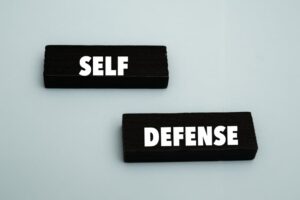 A coloured wooden block with text “SELF DEFENSE” on it