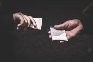 Hand of addict man with money buying dose of cocaine or heroine.