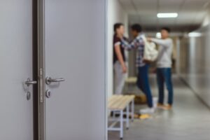 Blurred shot of schoolboy being bullied by classmates in school corridor